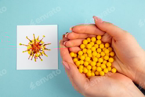 Preview: top view female hand with yellow vitamine pills on blue background hospital covid- cure drug lab