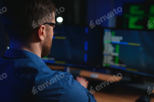 Preview: Night Office: Young Handsome Man in Working on Desktop Computer. Digital Entrepreneur Typing Code