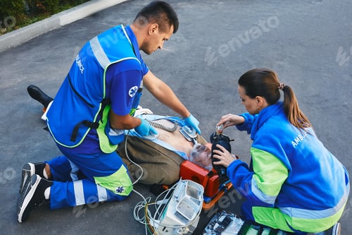 Preview: Team of paramedics performing CPR with mobile defibrillator and preparing manual resuscitator for
