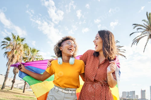 Preview: Lesbian loving couple looking at each other with rainbow flag.
