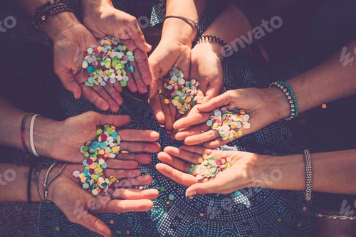 Preview: Close up of 4 people hands taking coloured confetti - sunlight and carnival party celebration