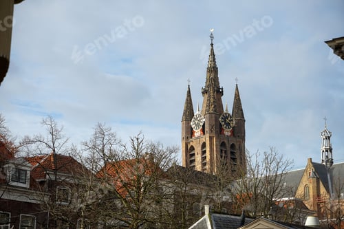 Preview: Old Church on blue cloudy sky background in Delft, Netherlands with naked trees in front