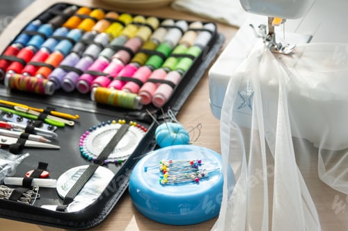 Preview: Sewing layout with multicolored spools of thread close-up, needles, electric sewing machine. Filling