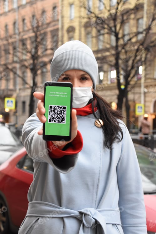 Preview: Woman holding smartphone displaying on app mobile valid digital green vaccination certificate