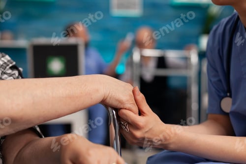 Preview: Assistant support worker holding disabled senior female patient hands