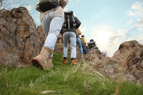 Preview: Group of hikers with backpacks climbing up mountains, closeup