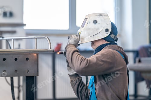 Preview: A man in welding helmet is working on metal in a building