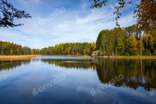 Preview: Calm lake in northern Minnesota with trees and rocks on a bright autum day