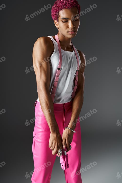 Preview: stylish african american man with curly pink hair looking down and posing with pink toy gun