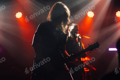 Preview: Guitarist performing live on stage with singer and red lighting