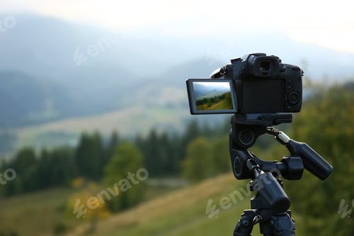 Preview: Taking video with modern camera on tripod in mountains
