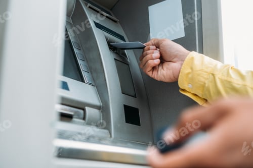 Preview: cropped view of bi-racial man putting credit card into atm machine