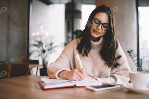 Preview: Smiling woman writing notes in notebook