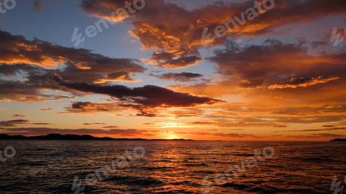 Preview: Scenic view of orange sunset sky over water with cloudy sky