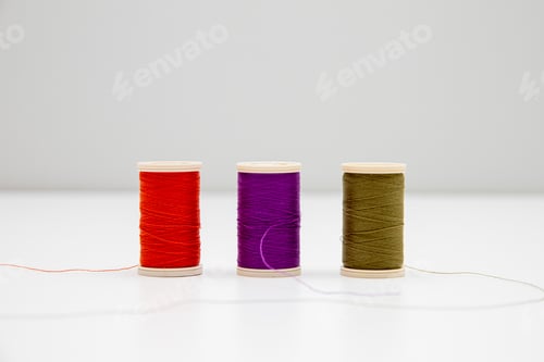 Preview: Closeup ofhree thread spools of red, violet, and swamp colors isolated in the light background