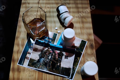 Preview: Above angle of wooden table with bottles with pills, photos and glass of whisky