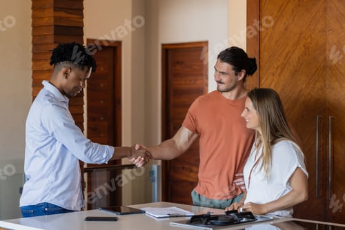Preview: Meeting at home, diverse friends shaking hands and smiling around kitchen table