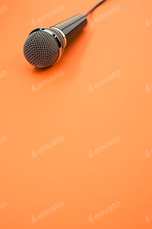 Preview: Vertical shot of a microphone on an orange surface