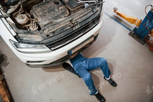 Preview: Top view. Employee in the blue colored uniform works in the automobile salon