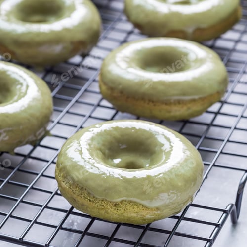 Preview: Freshly baked matcha banana donuts with matcha citrus glaze on cooling rack, square format