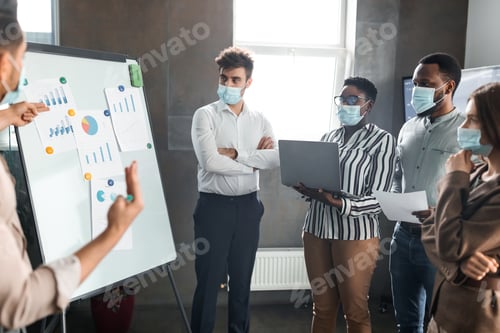 Preview: Employee in protective mask presenting business strategy on whiteboard