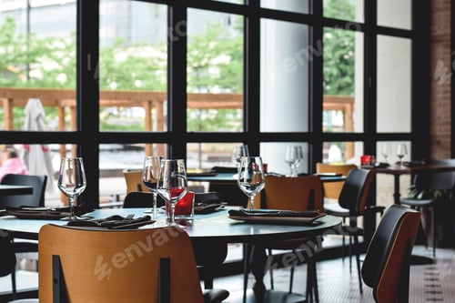 Preview: Empty tables set at restaurant with large wall to wall windows ready for guests