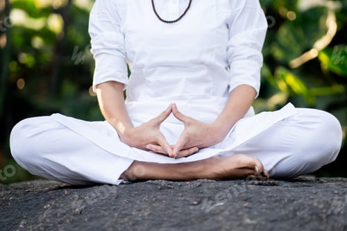 Preview: Woman in white practicing yoga outdoors.