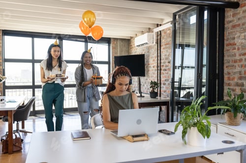 Visualização: Colegas surpreendendo mulher com bolo e balões na celebração moderna do escritório