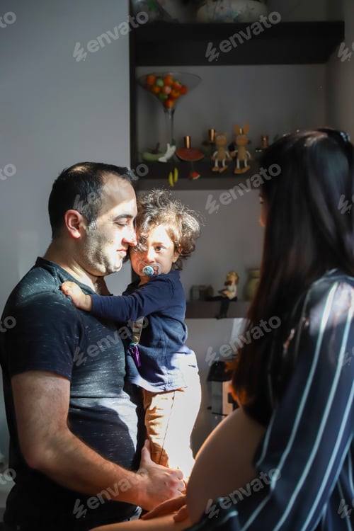 Preview: Father Holding Child with Woman in the Background