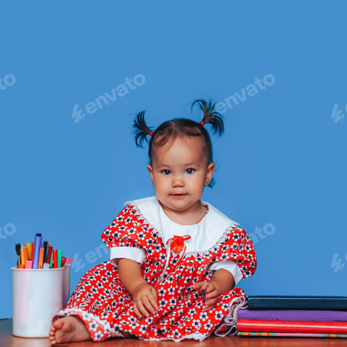 Preview: Cute one year old mixed race Asian Caucasian german girl wearing red dress smiles sweetly looking at