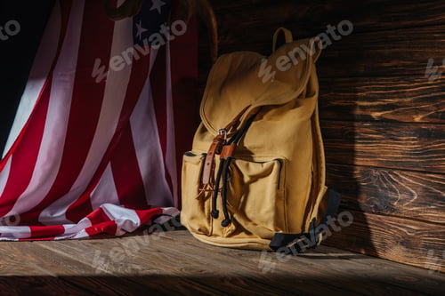 Preview: backpack and american flag on wooden surface, travel concept