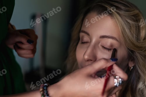 Preview: Woman Getting Makeup Applied Indoors With a Focus on Eye Makeup and Preparation