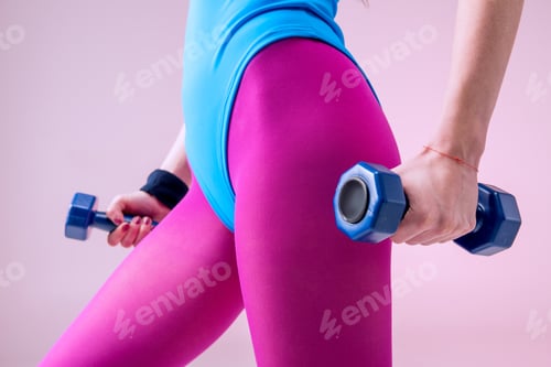 Preview: partial view of sporty woman holding dumbbells on pink