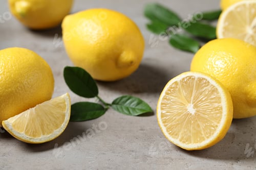Preview: Fresh lemons and green leaves on grey table, closeup
