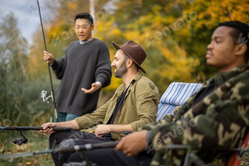 Preview: Man talking to male friends at fishing in nature