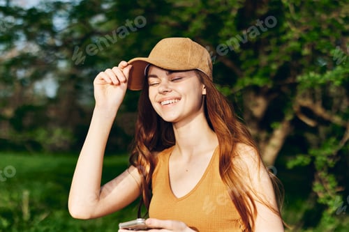 Preview: Woman blogger with phone in hand in nature against a backdrop of greenery smiling in the sunshine