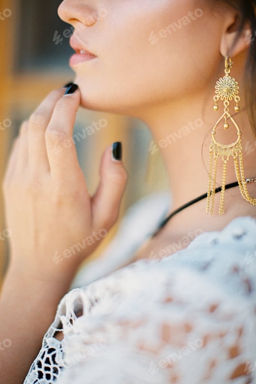 Preview: Young woman touches her chin with her fingers. Close-up