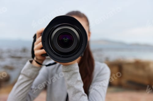 Preview: Young female photographer holding a camera outdoors, showcasing a serene expression and casual