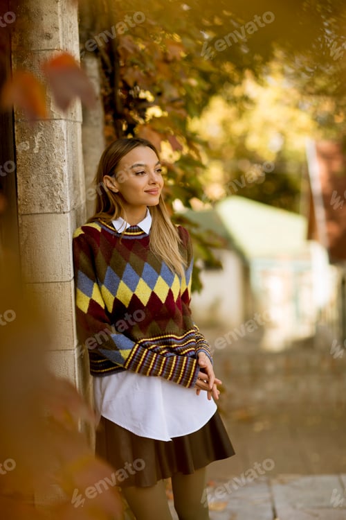 Preview: Young woman standing outside at sunny autumn day