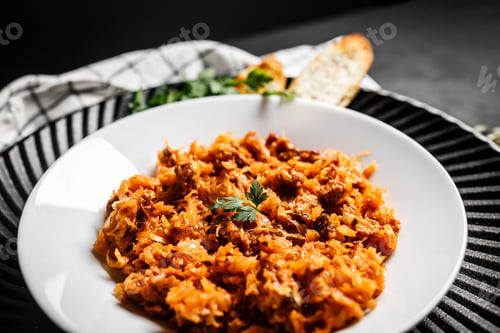 Preview: Top view of traditional Polish kraut stew bigos with sausage and meat on a black table.