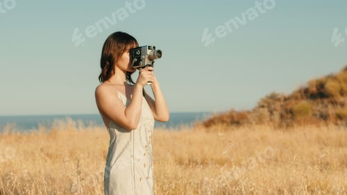 Preview: Pretty girl with vintage 8mm camera in the countryside