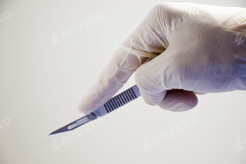 Preview: Isolated shot of a surgery knife in doctors hand with white gloves