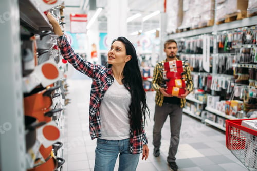 Preview: Young couple buying pans in supermarket