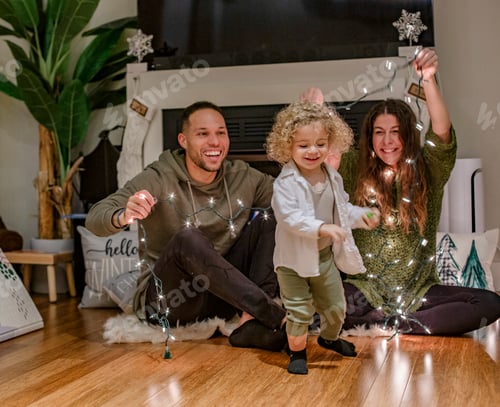 Visualização: Família feliz brincando com luzes de fadas no chão em casa durante a temporada de férias, Ohio, EUA