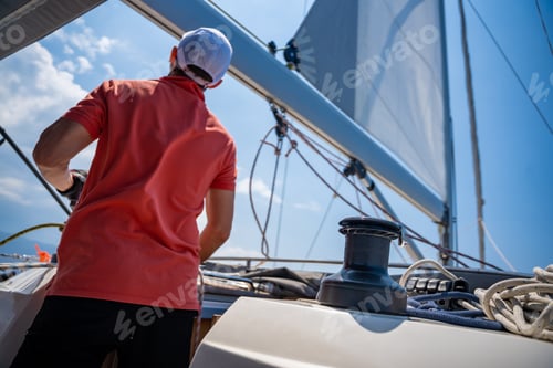 Preview: Mans pulling winch rope on sailing boat