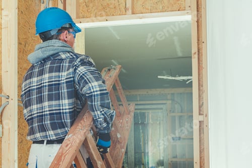 Construction Worker Carrying Ladder Inside Unfinished Home