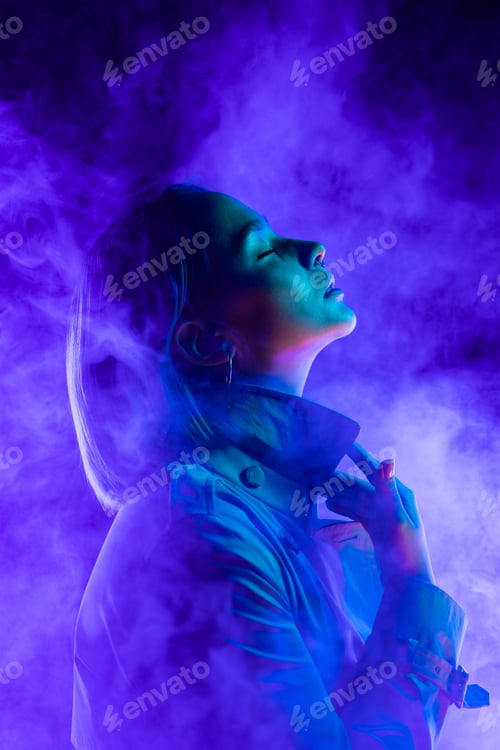 Preview: Young woman in neon multi-colors light on smoke, steaming background. stylish