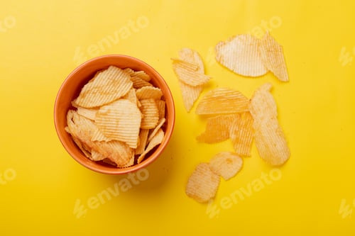 Preview: Overhead view of potato chips in bowl and on yellow background