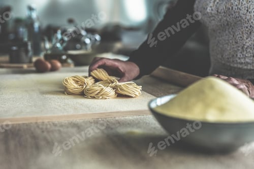 Preview: Closeup of homemade pasta - Senior woman making fresh italian traditional pasta inside factory