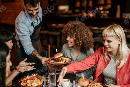 Preview: Waiter serving burger to happy customers in restaurant